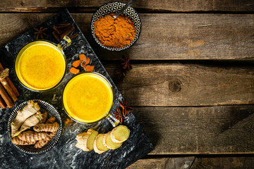 Turmeric golden milk and ingredients on wood background, copy space