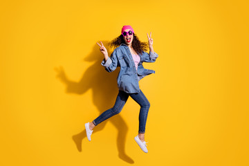 Fototapeta na wymiar Full length photo of funky curly lady jumping high going to party showing v-sign symbols wear casual trendy clothes isolated yellow color background