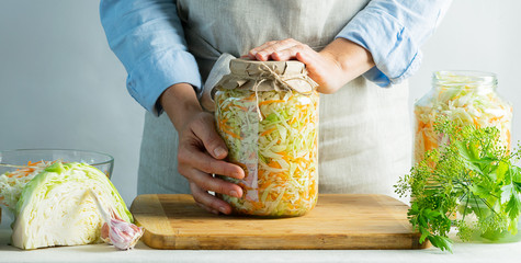 Fermentation preservation Sauerkraut in glass jars in the hands of a woman natural background....