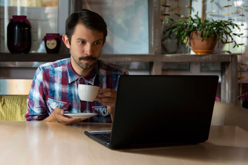 man watching a movie on the internet and drinking coffee