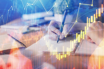 Financial forex graph drawn over hands taking notes background. Concept of research. Multi exposure