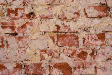 Wall of red crumbling brick, covered with white stucco, background