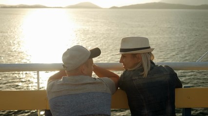 A man and woman in love looking at sunset from the deck of a cruise ship sailing the Mediterranean sea. Greece. 4K