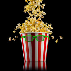 Flying popcorn from striped bucket isolated on black background
