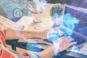 Double exposure of stock graph with businessman typing on computer in office on background. Concept of hard work.