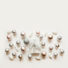 Christmas white and silver decoration, balls, gift box on white surface. View from above. Flat lay style.