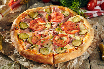 Pizza Restaurant Menu - Delicious Fresh Pizza with Tomato, Ham and Pickled Cucumber. Pizza on Rustic Wooden Table with Ingredients