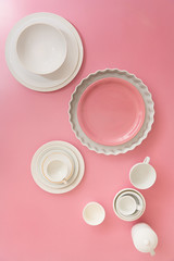 Various dish ware flat laid on top of pink background.