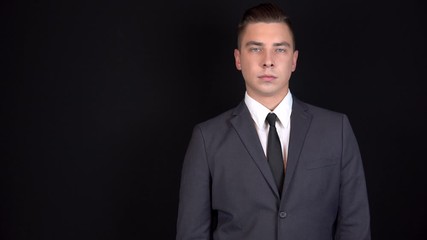 Young businessman clicks his fingers. Man in a black suit on a black background - Powered by Adobe