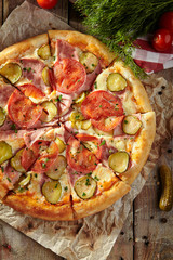 Pizza Restaurant Menu - Delicious Fresh Pizza with Tomato, Ham and Pickled Cucumber. Pizza on Rustic Wooden Table with Ingredients