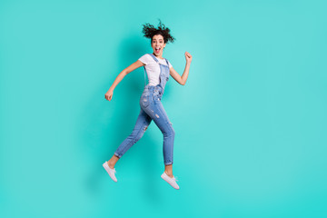 Full length body size view of nice attractive cheerful cheery glad girl wearing overall jumping strolling spending free time isolated on bright vivid shine vibrant green turquoise background