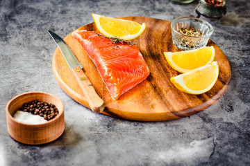 Slices of Salted smoked raw salmon with peppercorns and rosemary on a gray background.