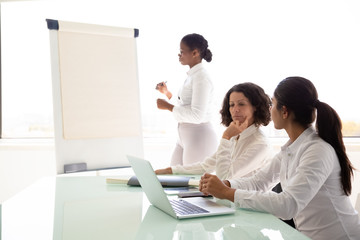 Business coach working with trainees in conference room. Young female speaker standing at flipchart...