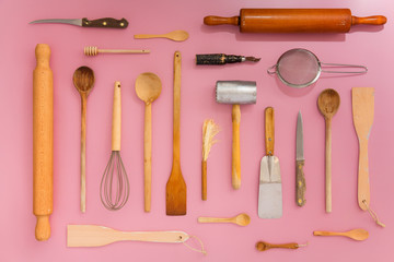 Top view of various kitchen utensils, against pink seamless background.