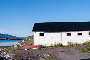 Obraz premium Norway white house with red old wood boat. Wood build. Scandinavian style
