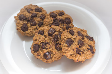 Four cookies with chocolate chips on a white background