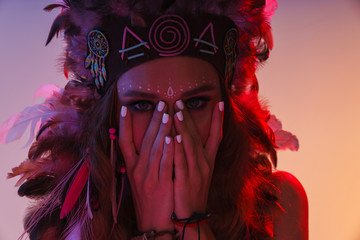 Indian woman in carnival suit isolated with neon lights covering face.