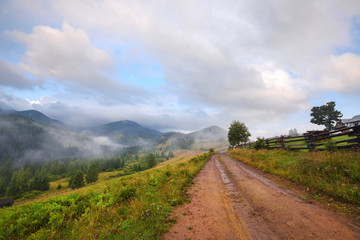 Amazing mountain landscape with fog and with a dirt road. Autumn morning in the Carpathians