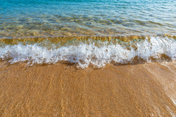 Small wave splashing on golden sand with blue sea water, Corsica, France