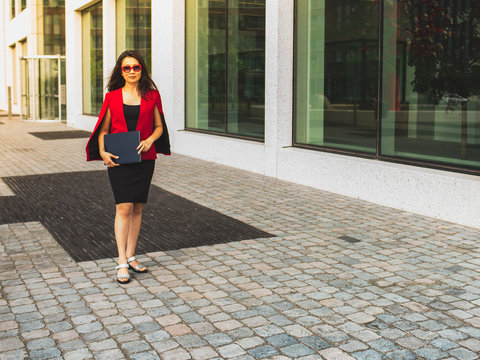 Asian Business Woman Walking To Office Building In A City Street With Paper Documents. Copy Space, View From Below.