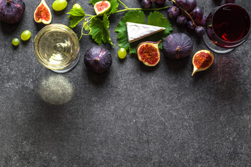 Fresh wine and cheese tasting. Glass of white and red wine and food, french cheese, figs and grapes.