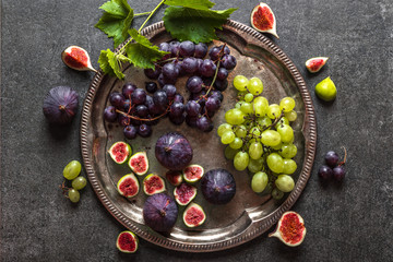 Healthy diet background. Raw organic fruits, fresh figs, red and green grapes on plate.