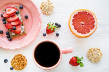Healthy breakfast with fruits, tasty toasts and fresh black coffee on white table, flat lay. 