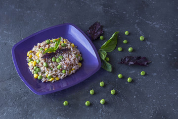 Obraz na płótnie Canvas Plate with tasty brown rice and vegetables on a dark background. The concept of vegetarian food. Organic foods and fresh vegetables.