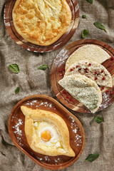 Set of Georgian and Adjarian Khachapuri Dishes, Kutabs and Chebureks on Rustic Tablecloth Burlap Background