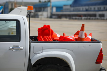 Details with the back of a truck carrying orange traffic safety cones on the runway of an airport