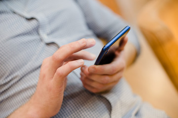 closeup of young man hands and fingers touching screen of mobile device blue cell phone