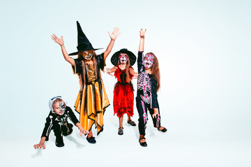 Kids or teens like witches and vampires with bones and glitter on white background. Caucasian models looks scary and playful. Halloween, black friday, sales, autumn holidays concept. The night of fear