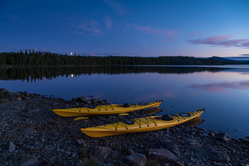 Two kayaks on the shore of a lake during a tranquil evening. Jamtland, Sweden.