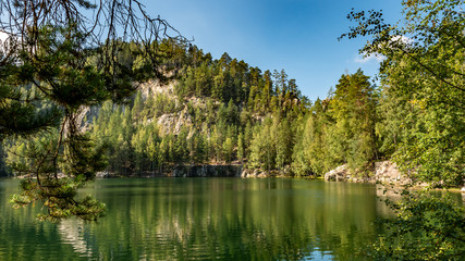 Lake and ancient pines growing between them located in rock city Adrspach, National park of Adrspach, Czech Republic 
