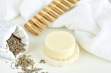 Fototapeta na wymiar Solid shampoo bar with lavender, wooden hair comb and white towel on background, zero waste bathroom