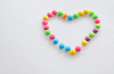 Place colorful candies into concept of heart symbol. Love and colorful concept.