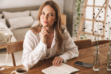 Serious business woman sit indoors in office writing notes.