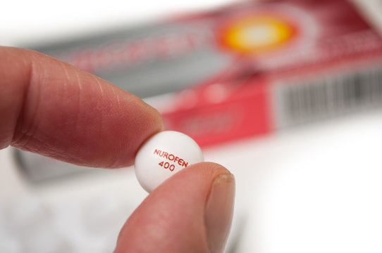 Mulhouse - France - 18 September 2019 - Closeup of pill of Nurofen in hand on nurofen cardboard box background