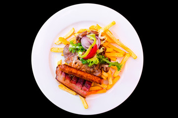 Several types of meat with fries on a plate.