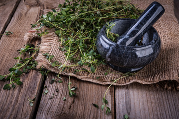 marble mortar with fresh green thyme on the wooden background
