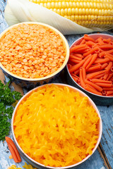 Yellow and orange gluten free diet pasta made from lentils and corn cereal on blue wooden table