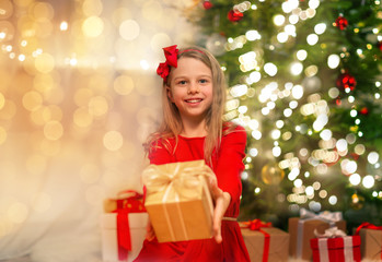 christmas, holidays and childhood concept - smiling girl in red dress with gift box at home