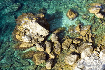 View from above, stunning aerial view of a limestone cliff and rock formations bathed by a turquoise clear water, Bonifacio, South of Corsica, France.