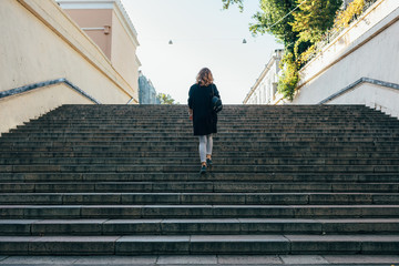 Woman with curly hair up the stairs