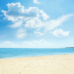 clouds in blue sky over sea and sand