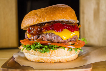 Closeup burger with beef cutlet, vegetables, cheese and lingonberry sauce.