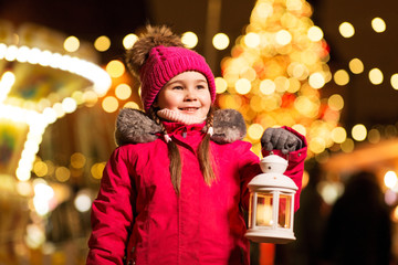holidays, childhood and people concept - happy little girl with lantern at christmas market in winter evening © Syda Productions