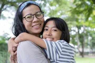 Obraz premium Asian mother and daughter hug each and smiling other at the park, Happy family concept.