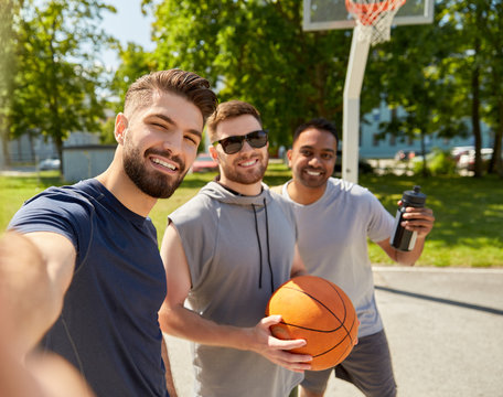 sport, leisure games and male friendship concept - group of happy men or friends taking selfie on outdoor basketball playground - Powered by Adobe