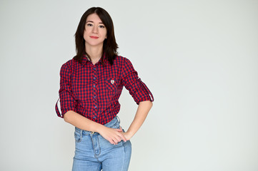 Portrait of a pretty asian brunette girl with black hair in a burgundy shirt and blue jeans on a white background. It stands right in front of the camera, with emotions in various poses.